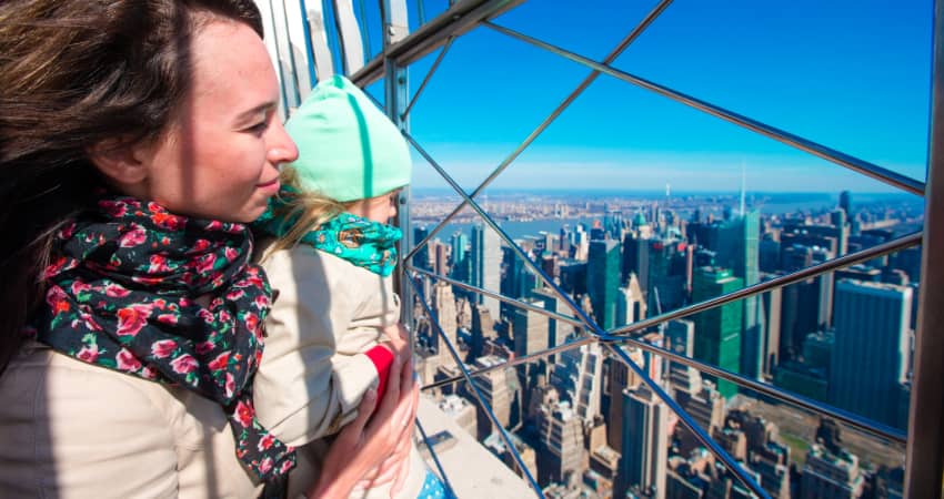 A mother and child stand at the top of the Empire State Building and take in the view