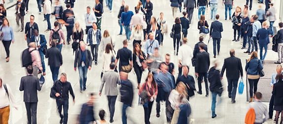 a large crowd of attendees navigate a convention floor