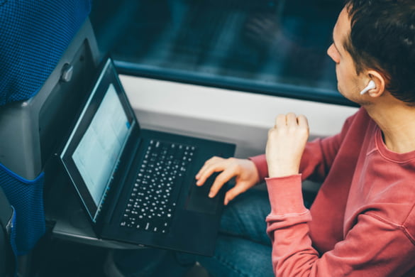 a man sits on a shuttle bus with his laptop