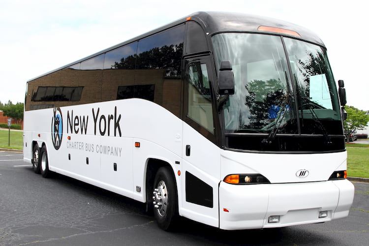 a bus from new york charter bus company sits in a parking lot before a trip